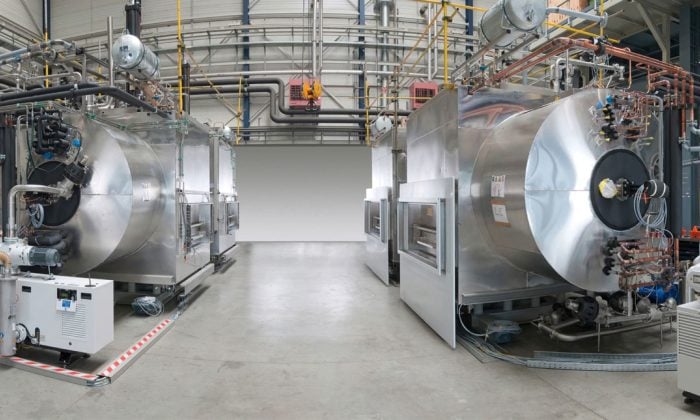 Two large stainless steel freeze-dryer units facing each other in an industrial hall