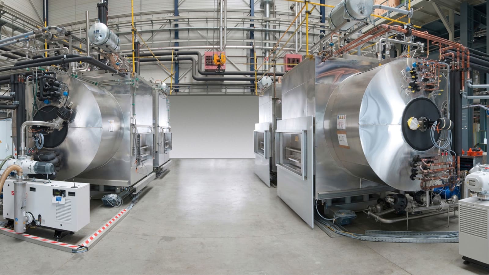 Two large stainless steel freeze-dryer units facing each other in an industrial hall